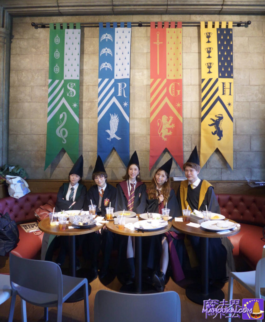 Commemorative photo of five Harriotta friends in dressing gowns & tongues hats. Tapestry of the four Hogwarts dormitories in the background. Harry Potter Former Toshimaen 'Restaurant' & 'Cafe' Butterbeer [Dining Report] Days 3 and 4 Warner Bros. Studio Tour Tokyo.